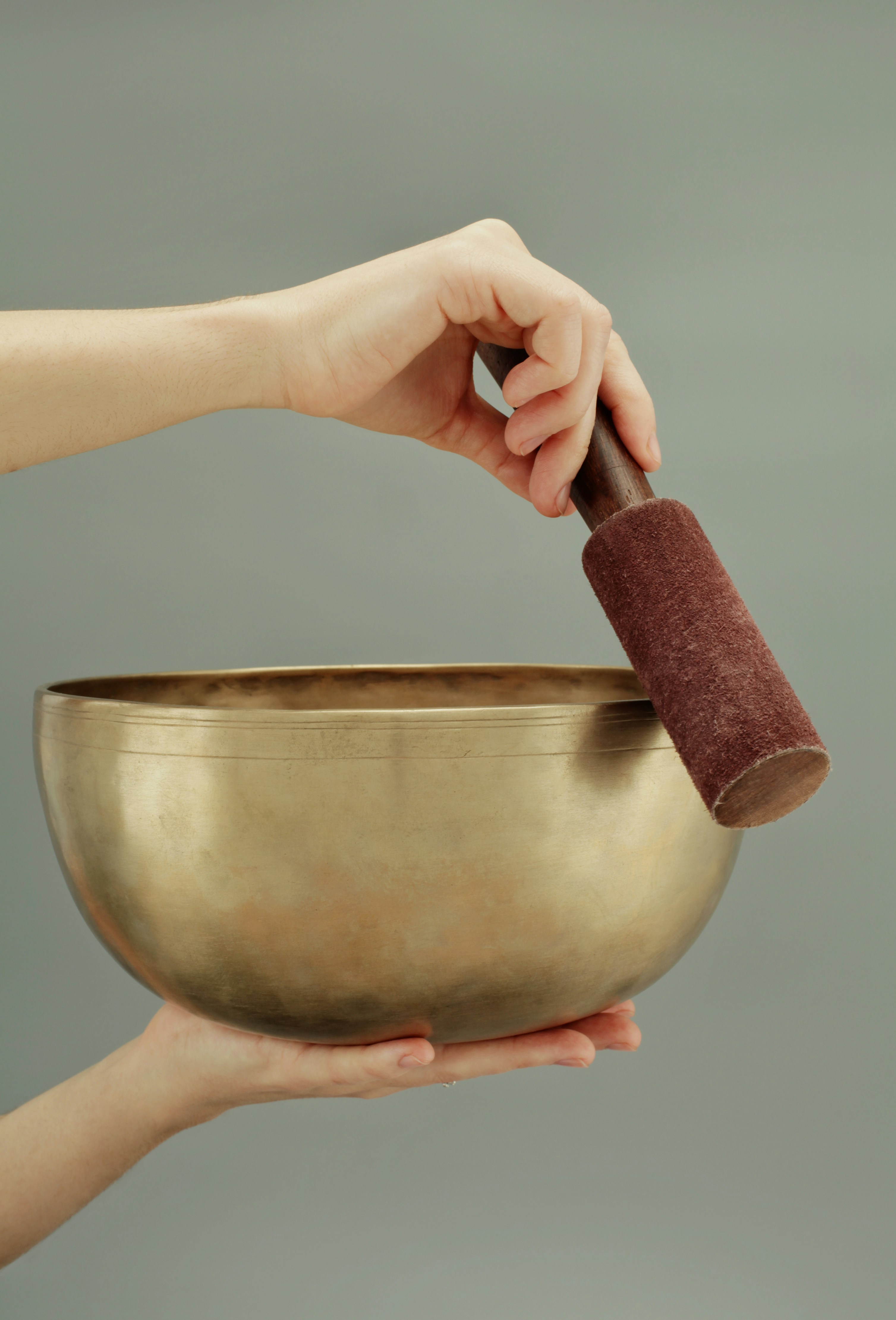 Hands holding a large Jambati singing bowl with mallet