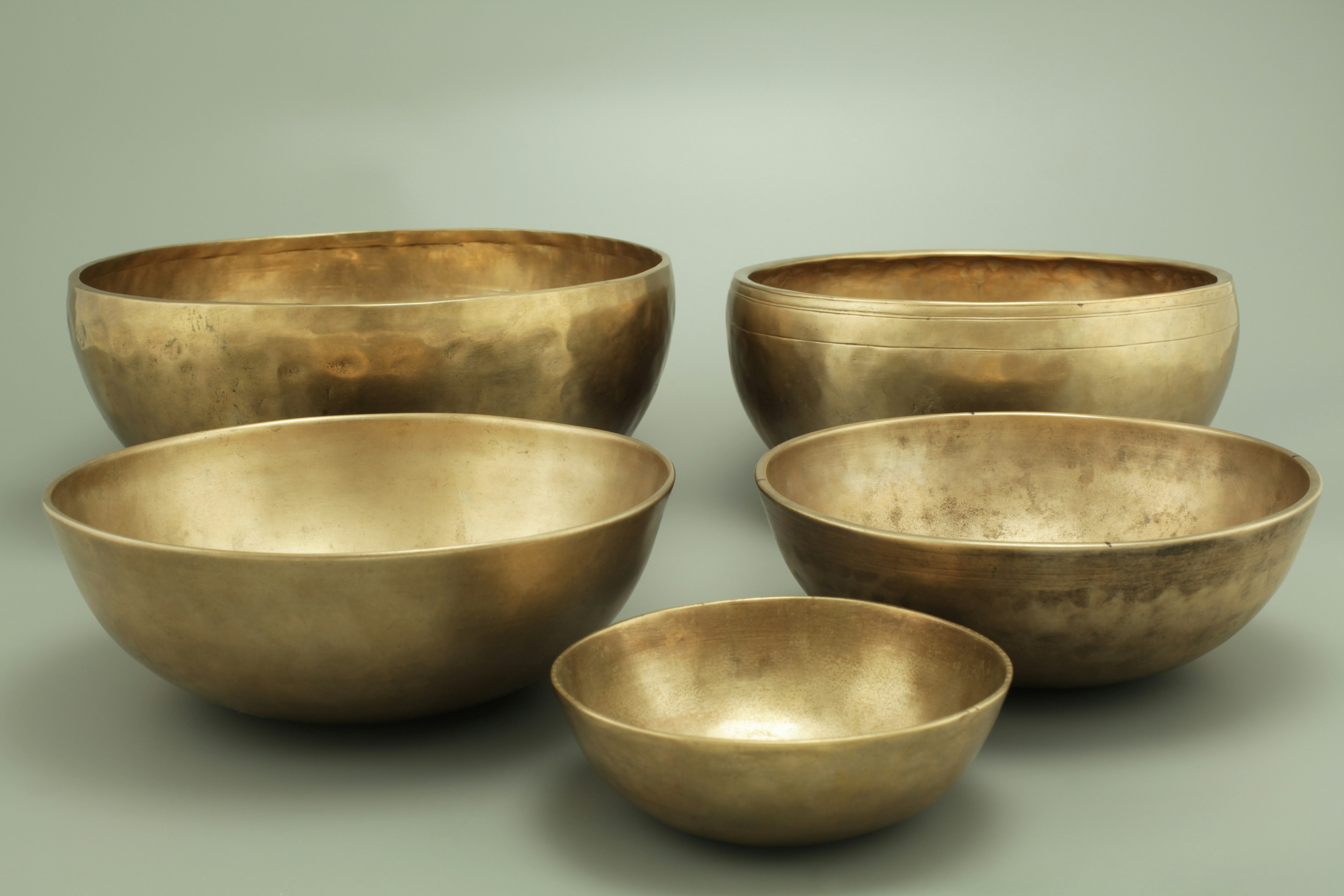 Five Himalayan Jambati singing bowls of varying sizes arranged together on a surface